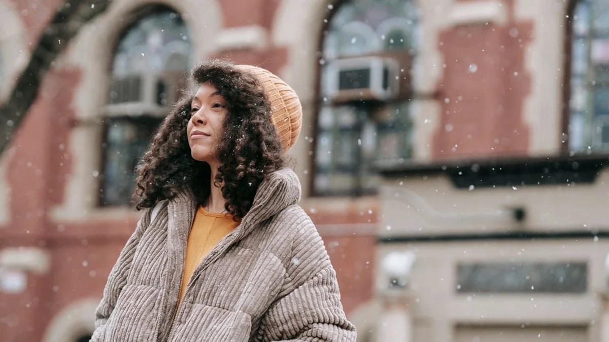 woman with curly hair walking outside in cold weather