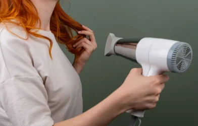 woman drying her hair with a white hair dryer at home