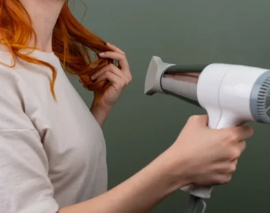 woman drying her hair with a white hair dryer at home