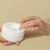 an open pot of curl cream held in one hand