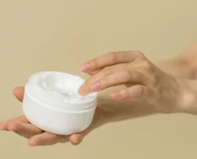 an open pot of curl cream held in one hand