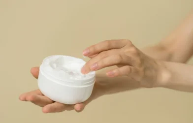 an open pot of curl cream held in one hand