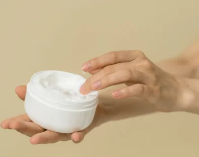 an open pot of curl cream held in one hand