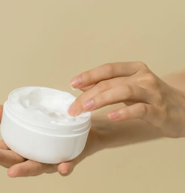 an open pot of curl cream held in one hand