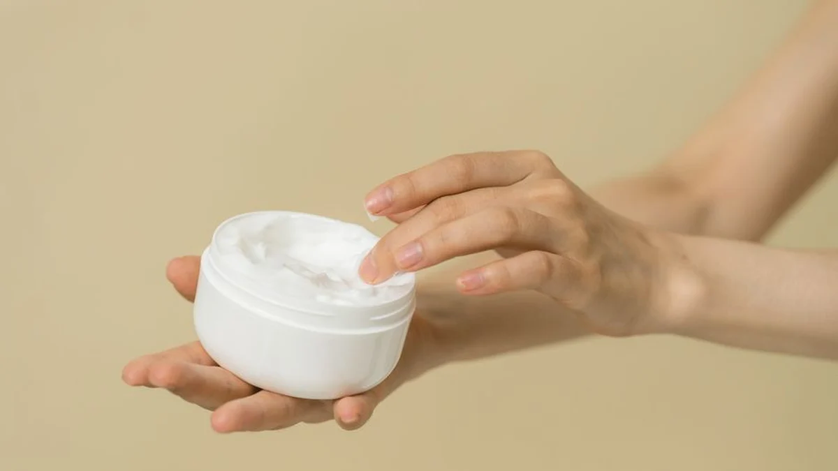 an open pot of curl cream held in one hand