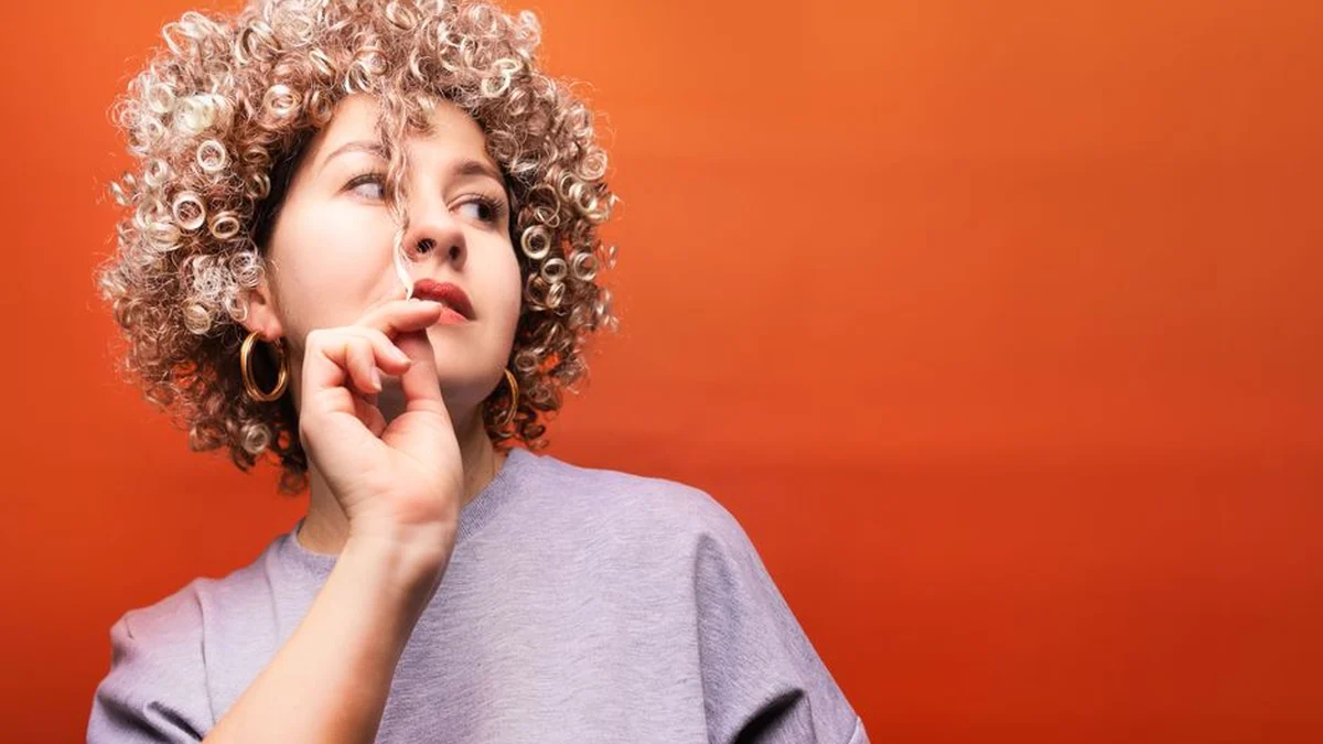 woman with full voluminous curls against an orange wall