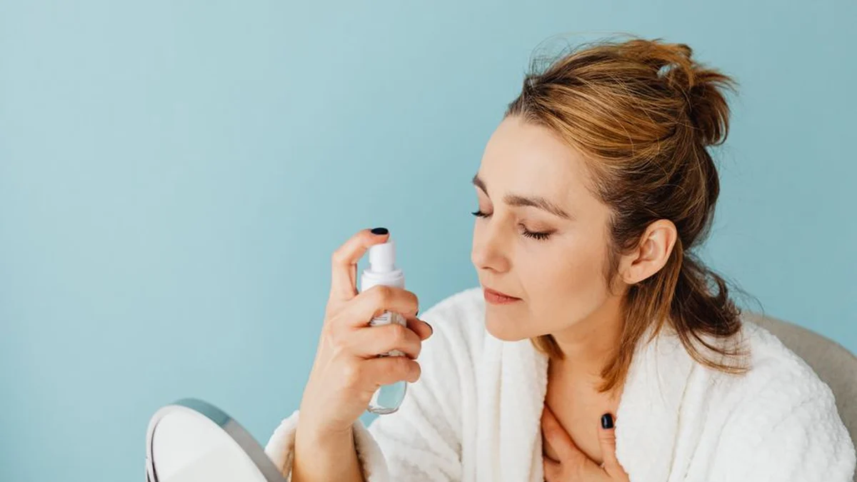 woman misting her hair at the bathroom mirror