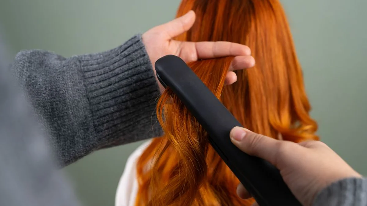 running a straightener down a section of hair