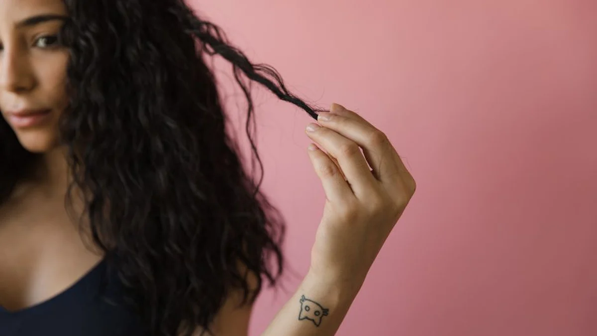 woman checking a single strand of her curly hair
