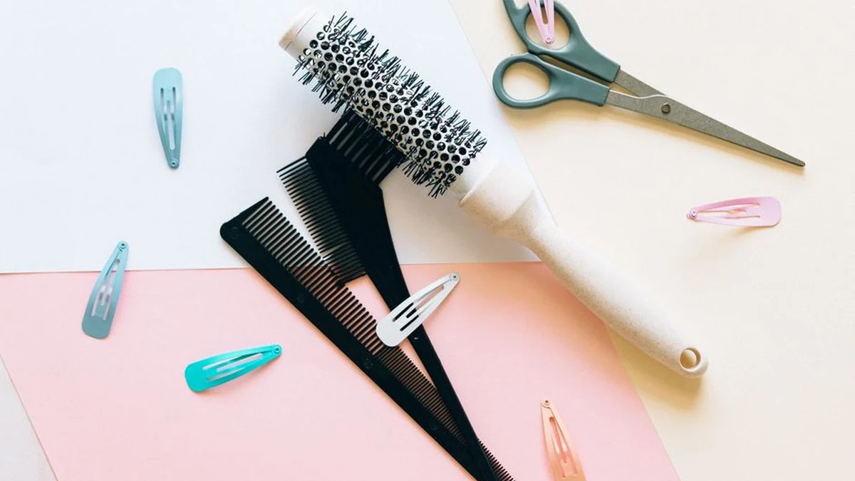round brush, clips and styling tools on a pink surface