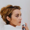 woman spraying her own hair with a finishing spray