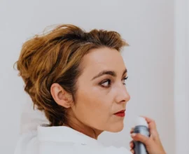 woman spraying her own hair with a finishing spray