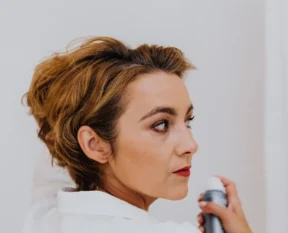 woman spraying her own hair with a finishing spray