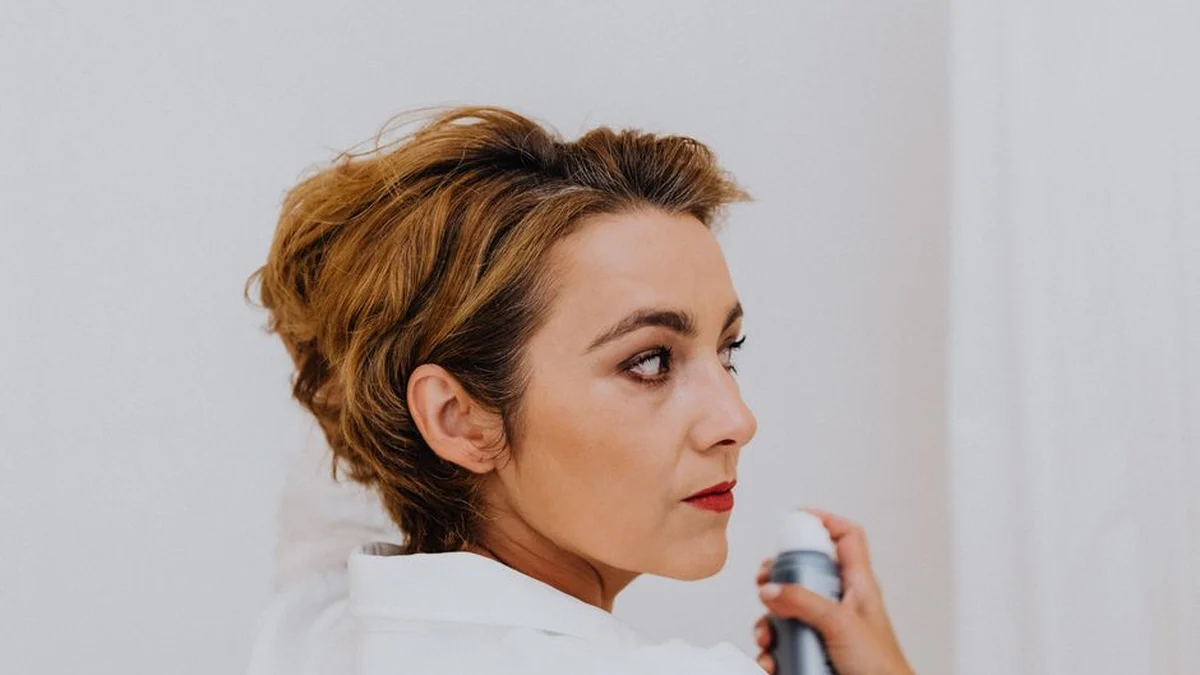 woman spraying her own hair with a finishing spray