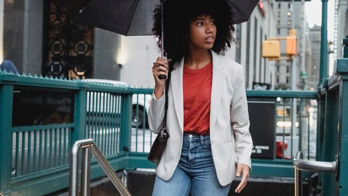 woman with curly hair holding an umbrella on a rainy street